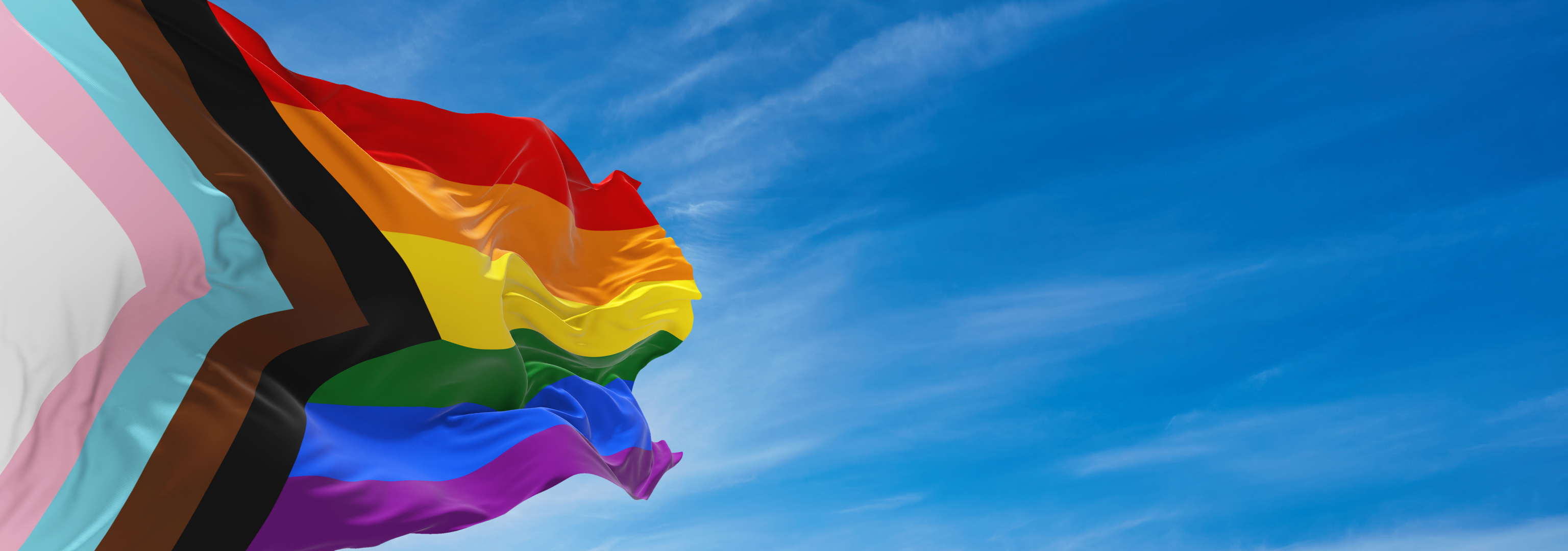 Waving Progress LGBTQ Rainbow Pride Flag on Blue Sky